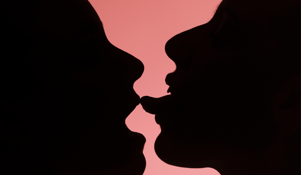 Silhouetted queer couple sharing a tender, consensual moment