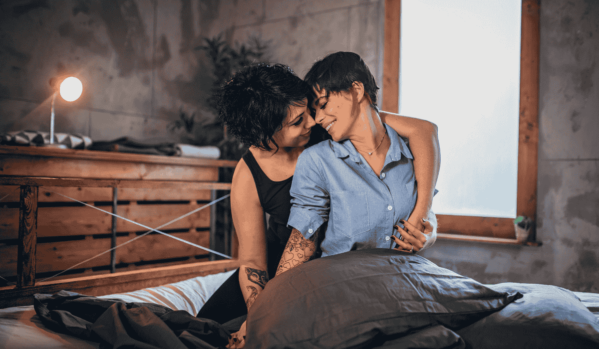 Sapphic couple sharing a soft, intimate moment in bed