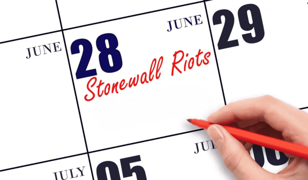 Hand marking June 28 as "Stonewall Riots" on a calendar.